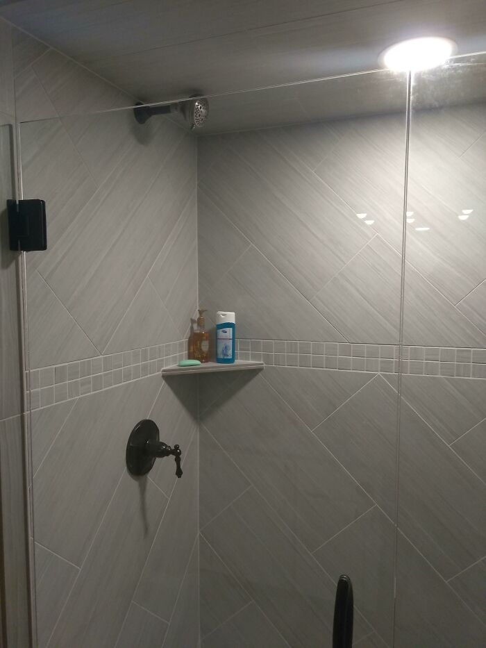 Questionable home improvement project: a shower with a shower head installed extremely high on the wall.