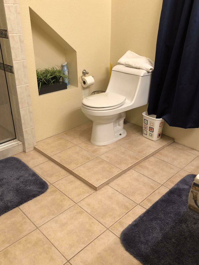 A toilet installed on a raised platform of tiles, showing questionable results from home improvement projects.