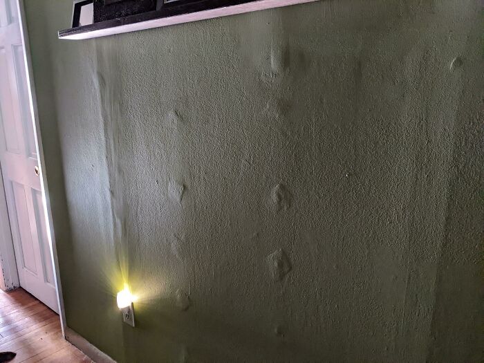 An indoor home improvement wall with visible bumps and imperfections, showcasing questionable results.