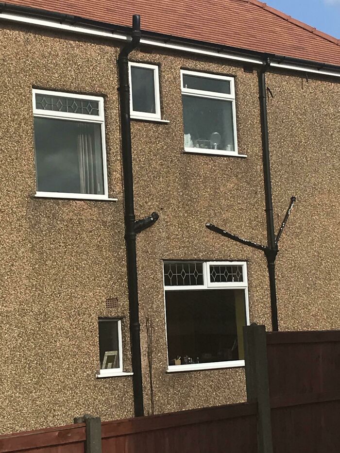 Exterior of a house with oddly placed home improvement drain pipes and windows, illustrating questionable results.