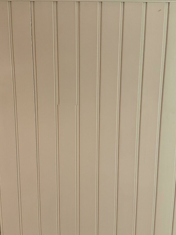 Close-up of a wall with mismatched vertical panels and noticeable gaps, a questionable home improvement project.