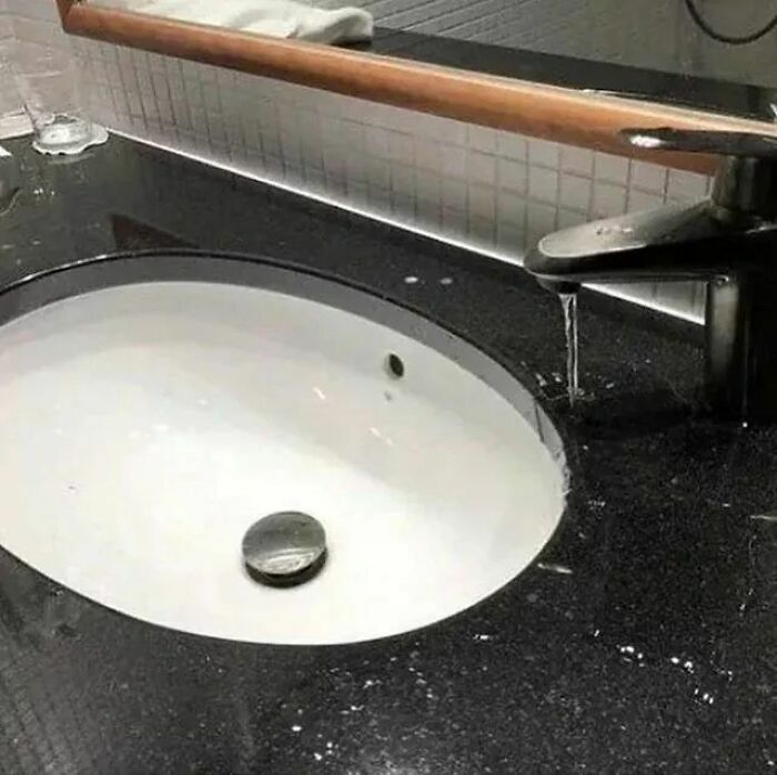 Questionable home improvement project with a bathroom faucet pouring water outside the sink basin.