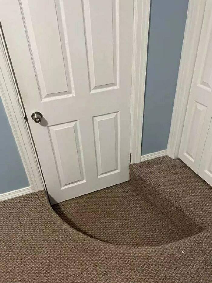 A white door with a circular cut-out at the bottom, allowing it to clear a step, revealing questionable home improvement projects.