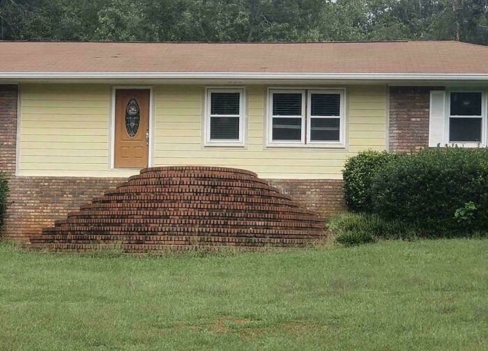 A home with brick stairs built against the entire front of the house, showing questionable home improvement.