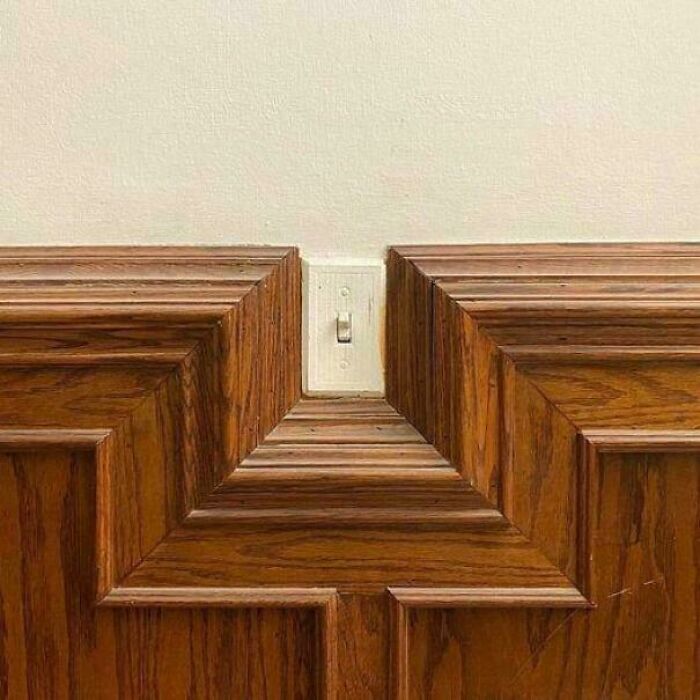 A poorly installed light switch cut into by wood trim, showing questionable results from a home improvement project.