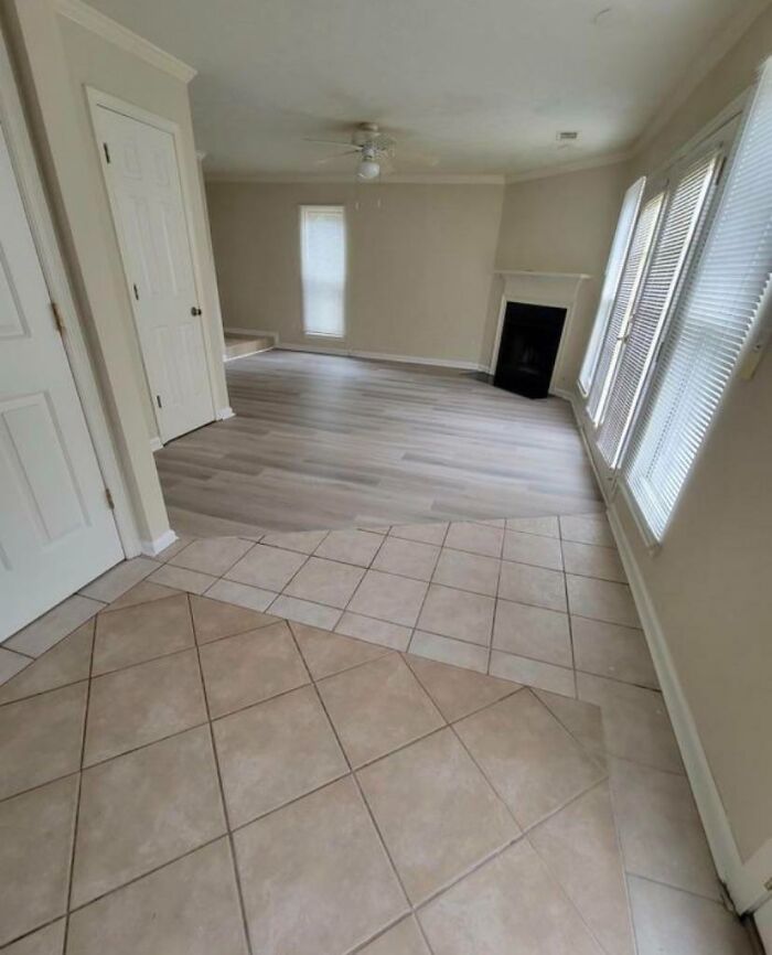An empty room with mismatched flooring, displaying questionable home improvement aesthetics.