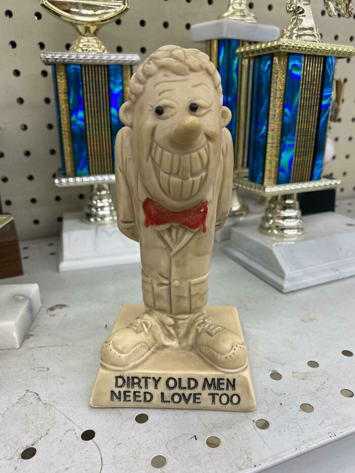 A humorous ceramic trophy depicting a man with a large smile and a red bowtie, an unhinged secondhand find.