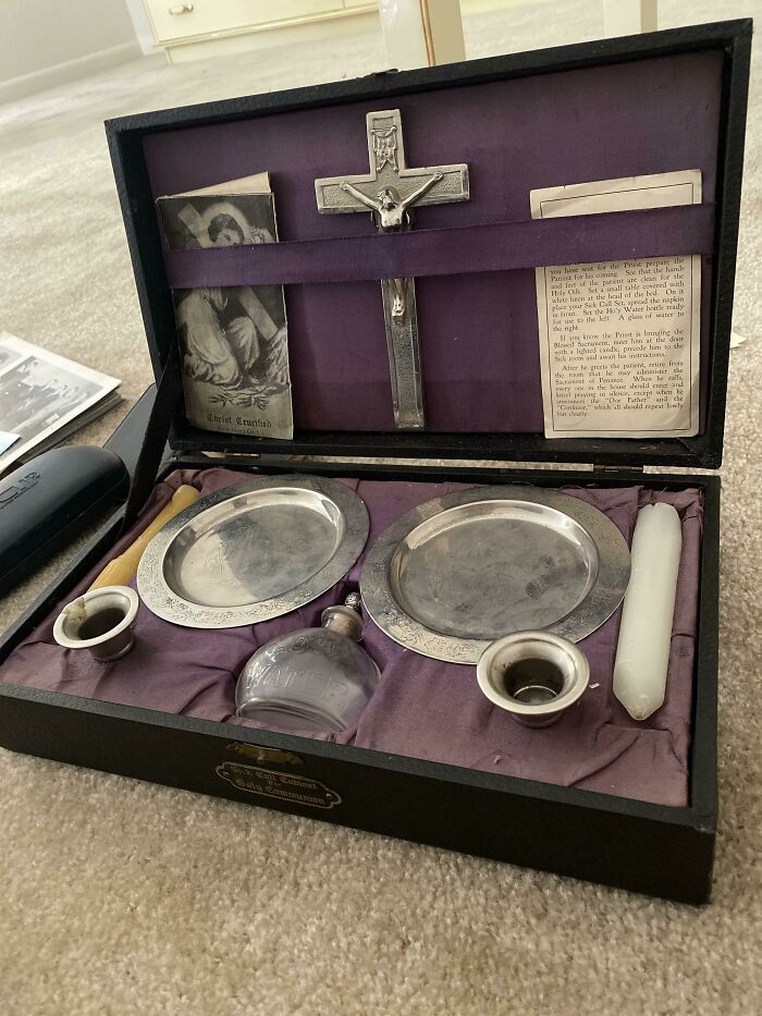 A dark wood box containing various religious items, including a crucifix and two silver plates, one of many unhinged secondhand finds.