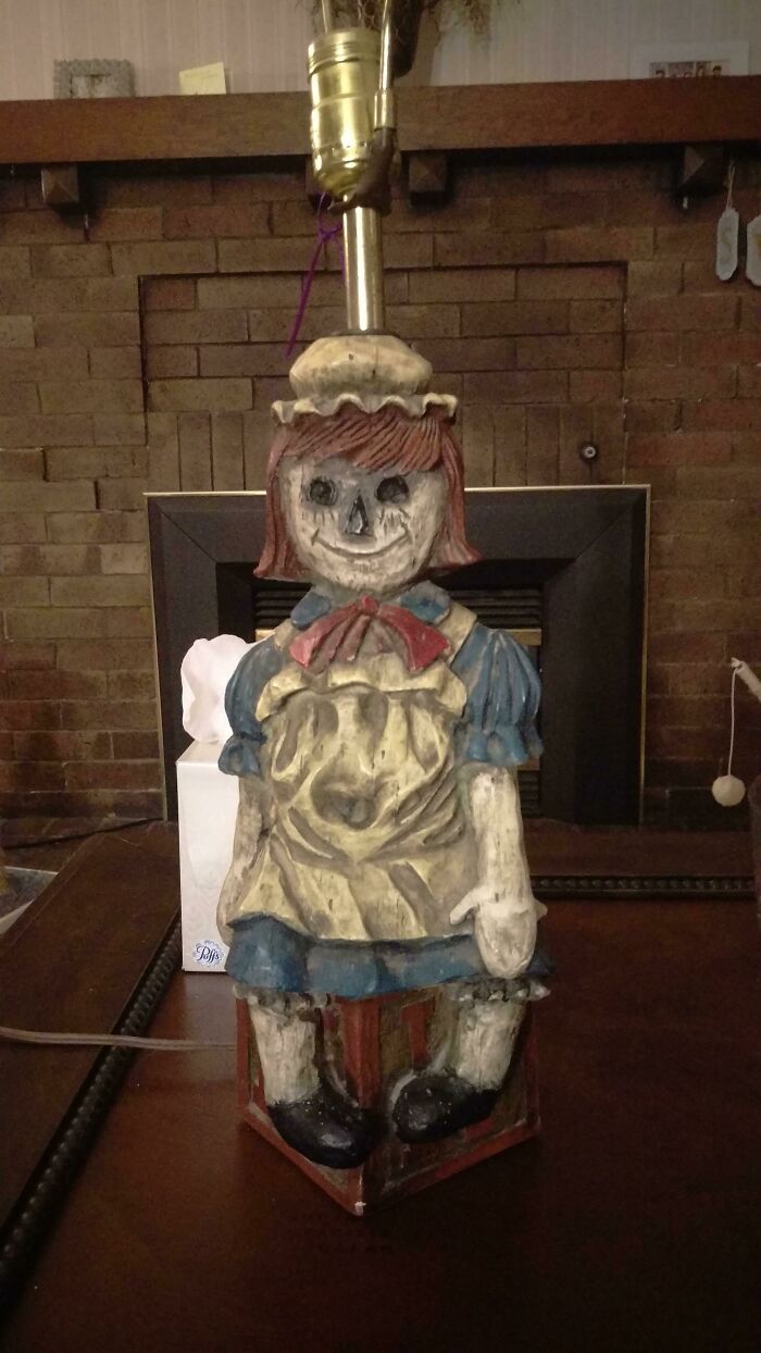 An eerie, carved wooden doll serving as a lamp base, a cursed treasure among secondhand finds.