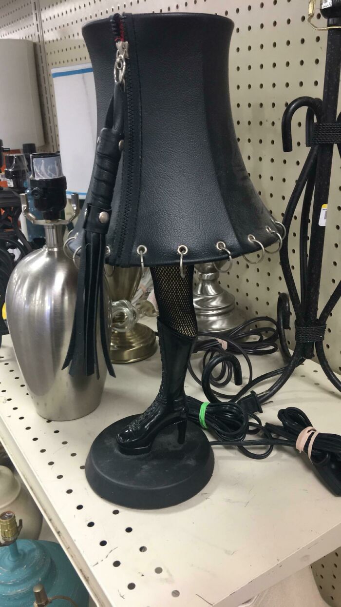 A black table lamp with a high-heeled boot leg base and a leather shade with a whip, a strange secondhand find.