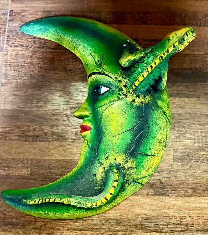 A vibrant green unhinged secondhand crescent moon wall art with a creature design.