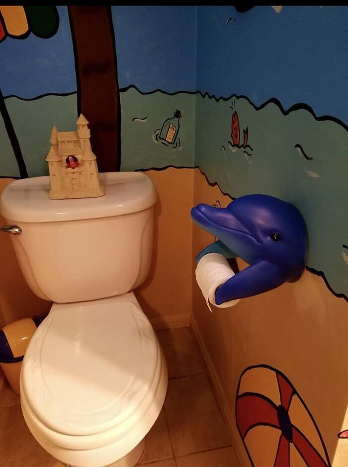 A bathroom with a dolphin toilet paper holder, an unhinged secondhand find.