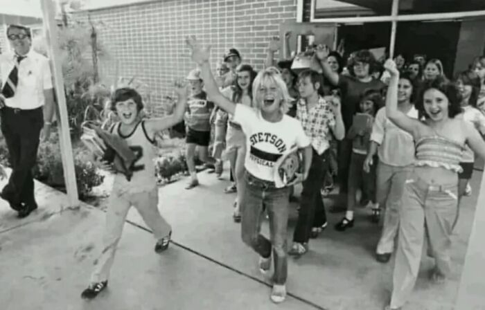 Candid old photo of excited children running out of school, revealing what the world looked like generations ago.