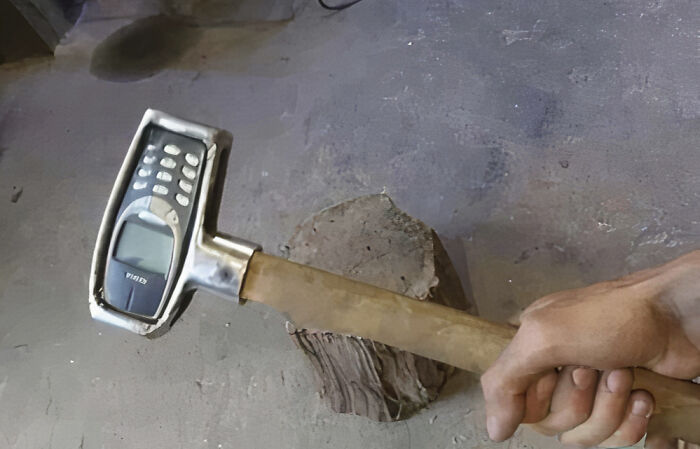 Hilarious photos: A hand holds a hammer with a Nokia phone head, designed for durability.