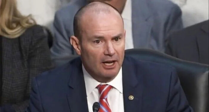 A man in a suit and tie speaking at a podium, demonstrating hypocrisy.