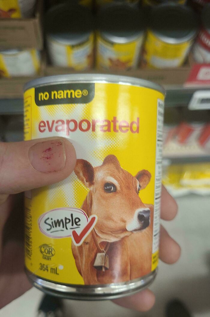 A hand holds a can of evaporated milk featuring a cow, depicting online lies.