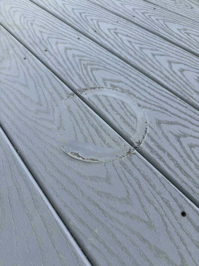 A large, light-colored stain on a wooden deck is a result of mischievous kids, causing parents a headache.