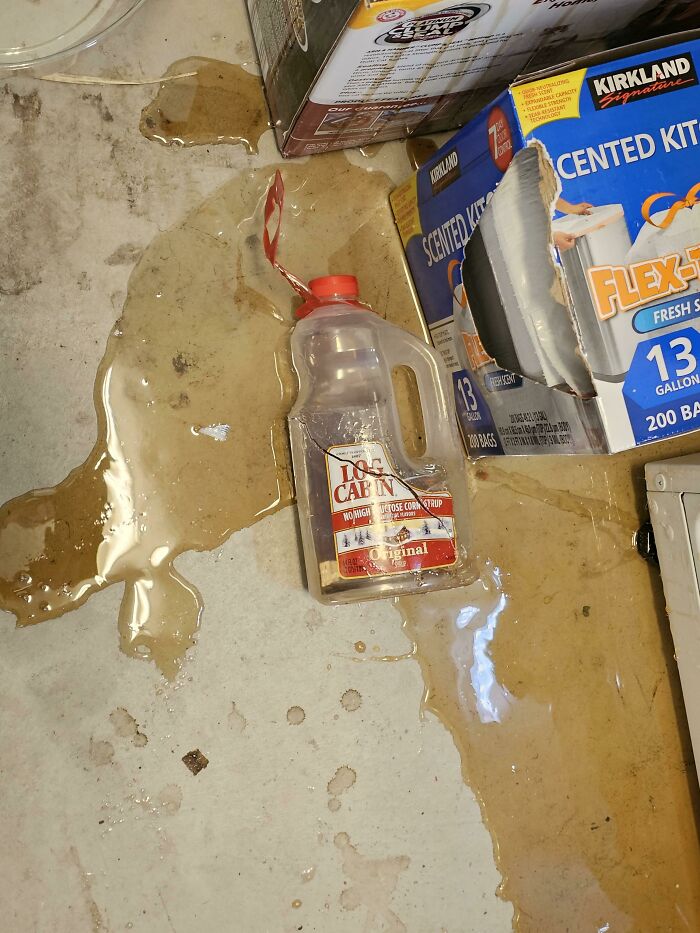 A spilled bottle of syrup on a dirty floor creating a sticky mess, highlighting the mischievous kids.