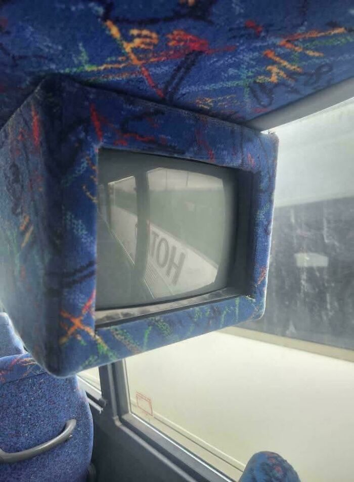 A small, square TV screen built into the ceiling of a bus, a nostalgic Aussie memory of public transport.