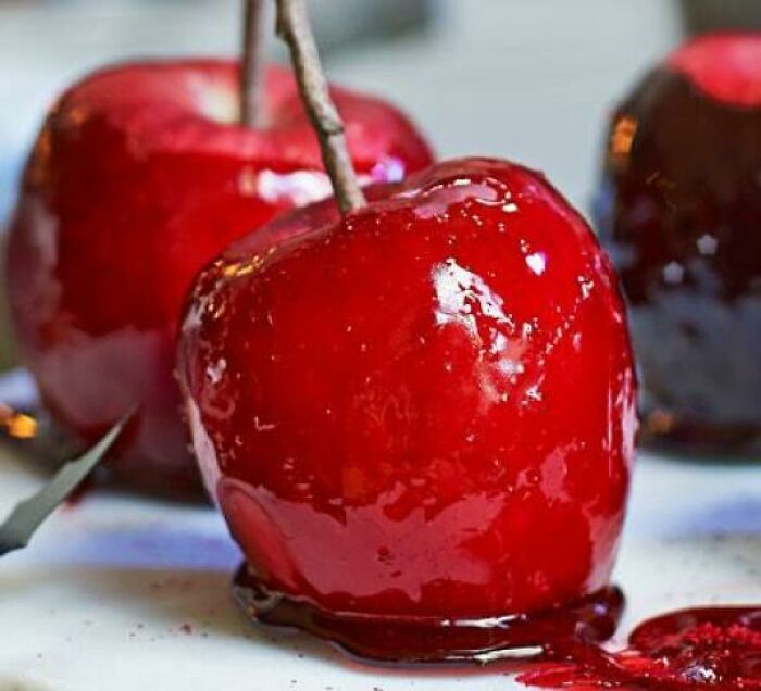 A close-up of a glossy, red candy apple with a stick, evoking nostalgic Aussie memories for many who grew up with them.