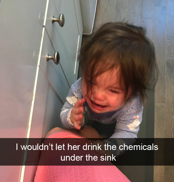 A crying mischievous kid, upset because they were prevented from drinking chemicals under the sink.
