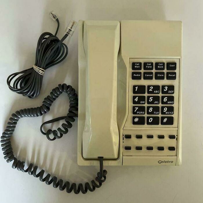 An old-fashioned cream-colored push-button Telstra corded telephone with a coiled cord, evoking nostalgic Aussie memories of communication.