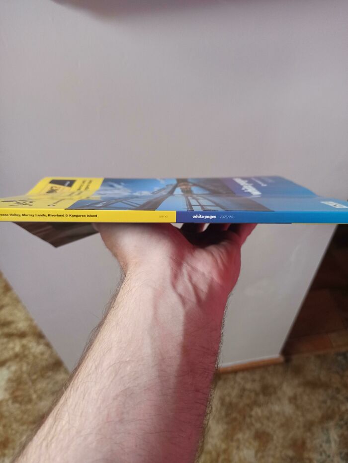 A hand holding an Australian White Pages phonebook, a nostalgic Aussie memory of communication past.