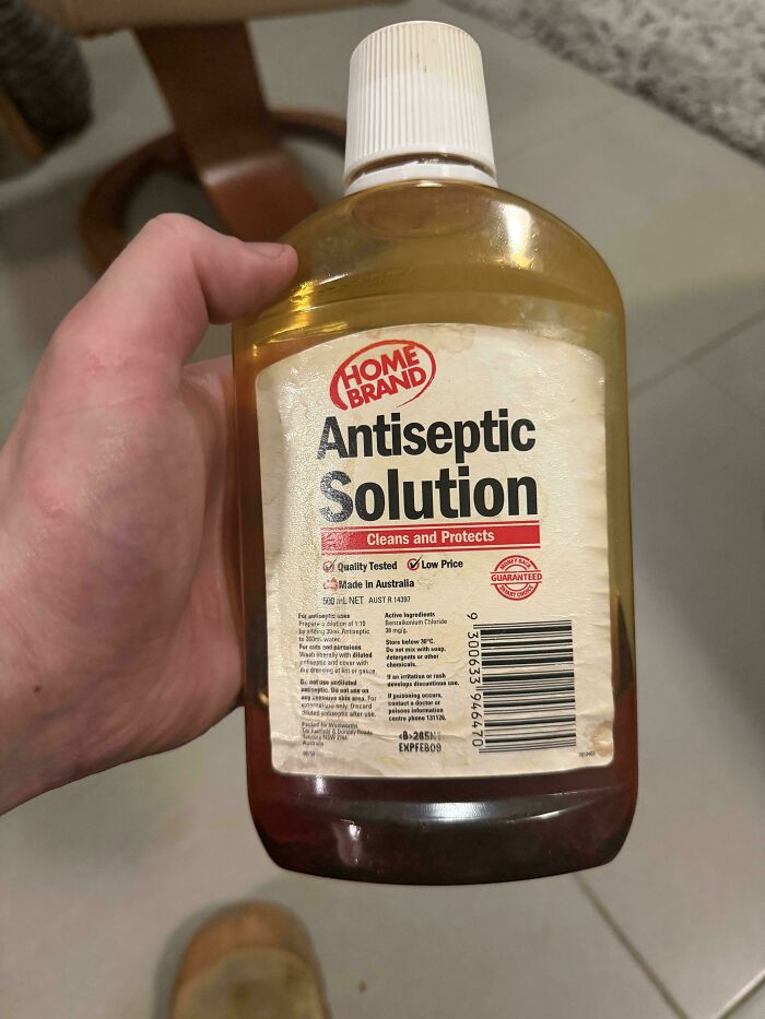 A hand holding a bottle of Home Brand Antiseptic Solution, a common item in many Aussie memories.