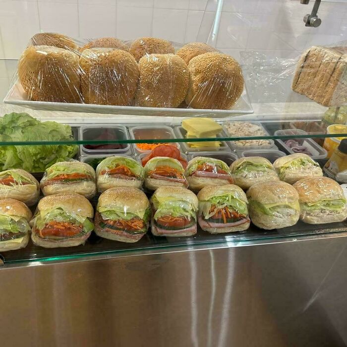 A display of freshly made, plastic-wrapped sandwiches and bread rolls, evoking nostalgic Aussie memories.