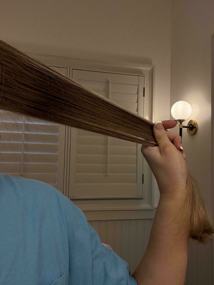 A person holding out a long, straight section of their hair, demonstrating a fascinating body quirk.
