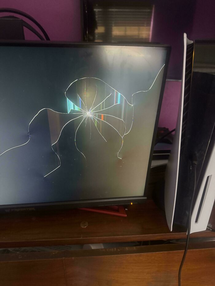 A shattered computer monitor screen next to a gaming console, damaged by mischievous kids