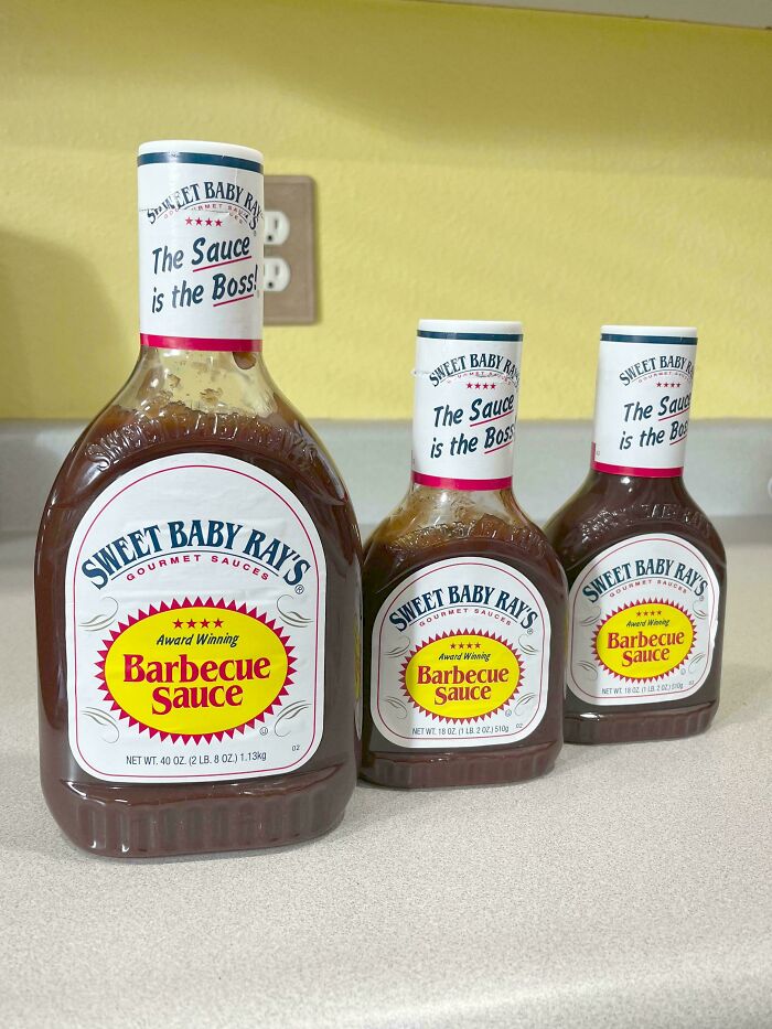 Three bottles of Sweet Baby Rays Barbecue Sauce on a counter, showing a funny parent moment.
