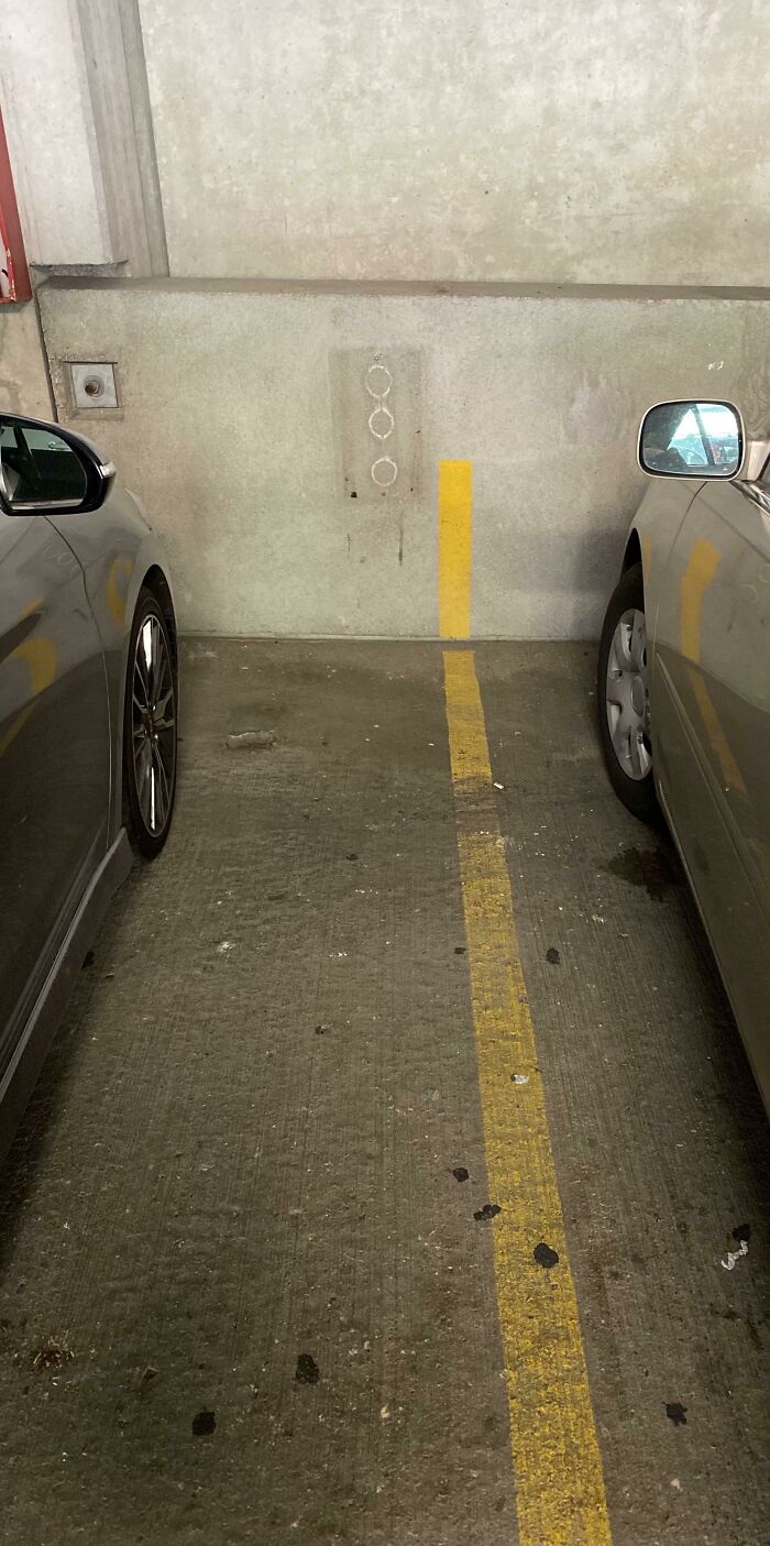 Tight parking space between two cars, a practical product design issue in urban areas.