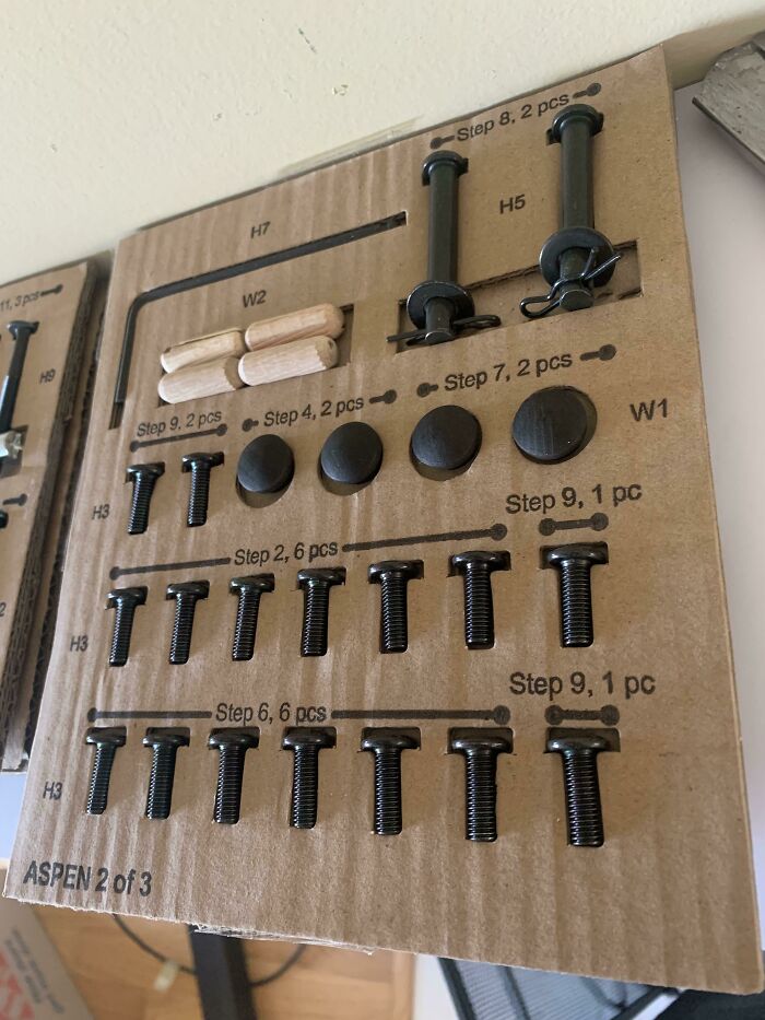 Various screws and wooden dowels neatly organized on a cardboard cutout, showcasing practical product designs for assembly.