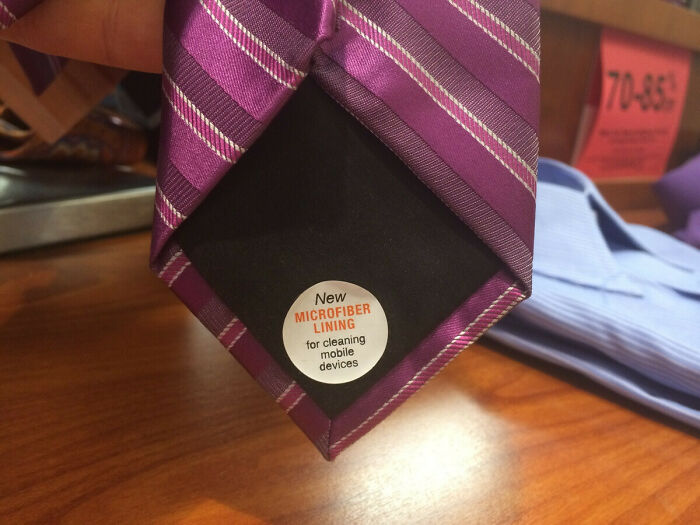 A purple striped tie with a label on the back indicating a new microfiber lining for cleaning mobile devices, a practical product design.