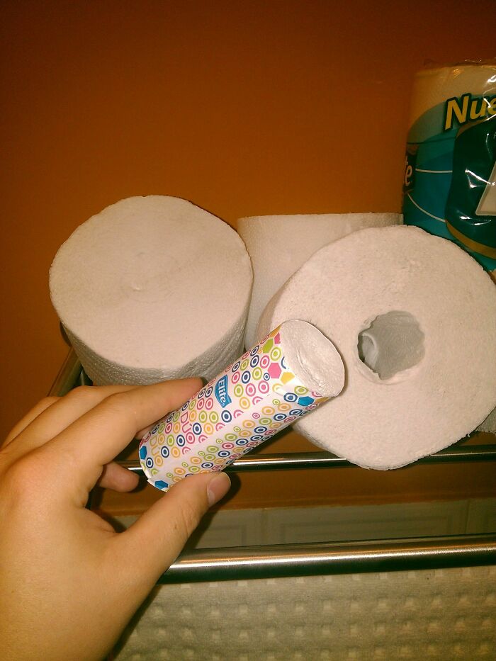 A hand holding a toilet paper roll with a patterned core, next to other rolls, showcasing practical product designs.