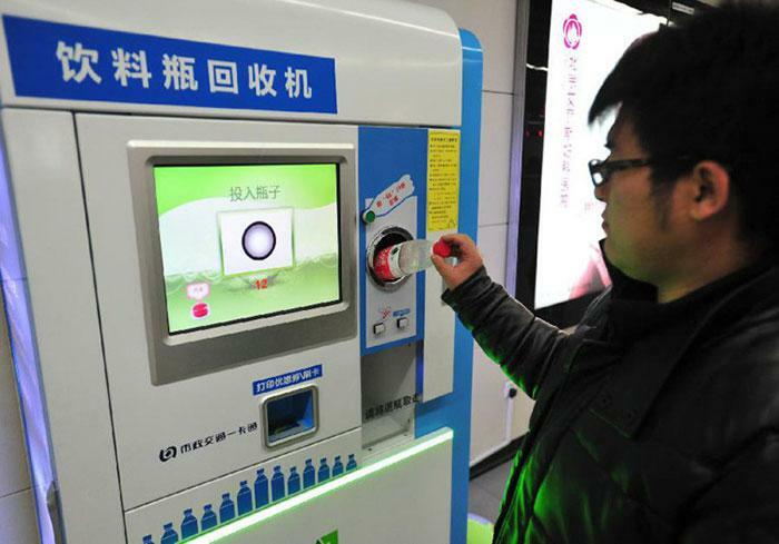 A man inserting a bottle into a recycling machine, demonstrating practical product designs for environmental solutions.