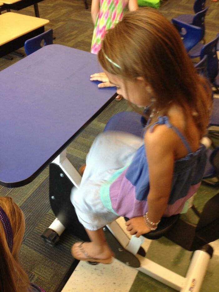 A young girl using a desk with pedal exerciser, an example of practical product designs for active learning.
