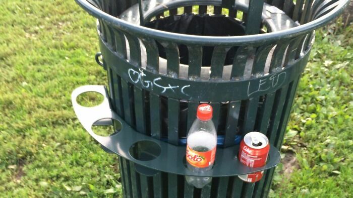 A trash can with a side shelf for practical product designs like drinks and cans in a park setting.