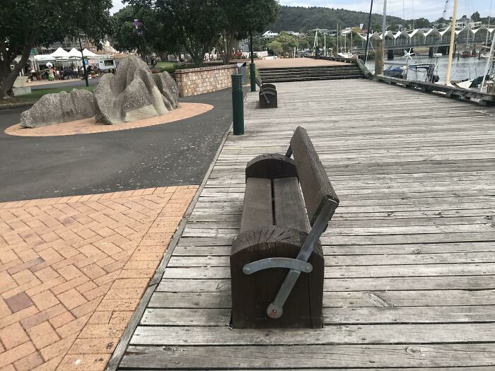 A wooden bench with a rotating backrest on a pier, a brilliant product design for comfort and versatility.