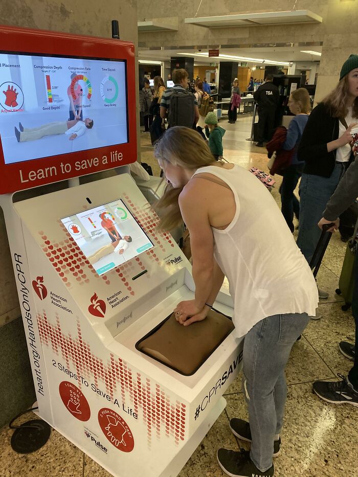 A woman practicing CPR on an interactive kiosk, a practical product design for learning life-saving skills.