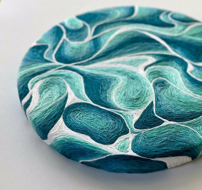 Close-up of circular embroidery projects with abstract wave patterns in shades of teal and white