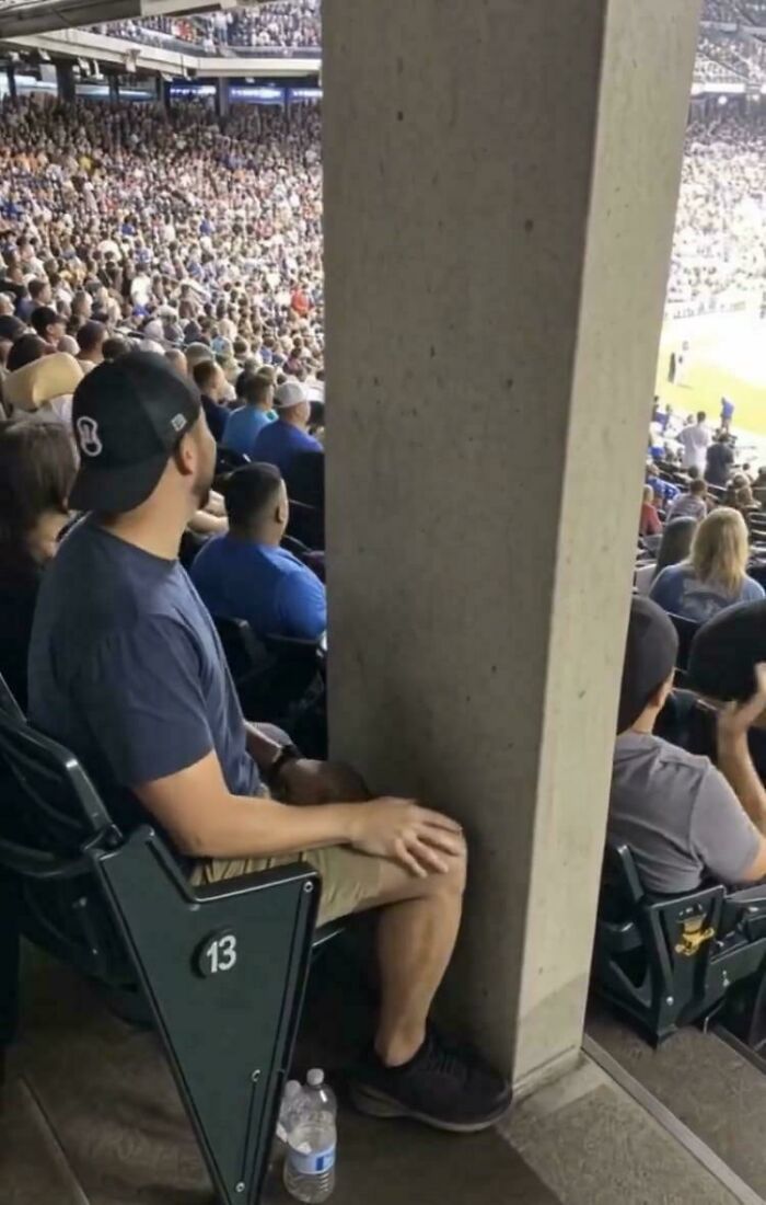 A man's view blocked by a large pillar in a stadium, an unhinged image that makes people go Hmmm.