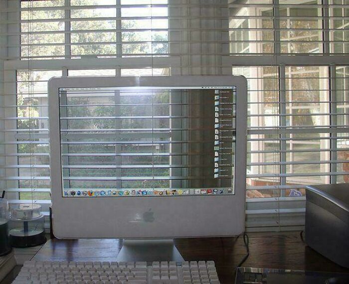 A computer monitor perfectly aligns with window blinds, creating unhinged images.