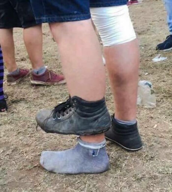 A person wearing a shoe on top of another shoe, an unhinged image of bizarre footwear.