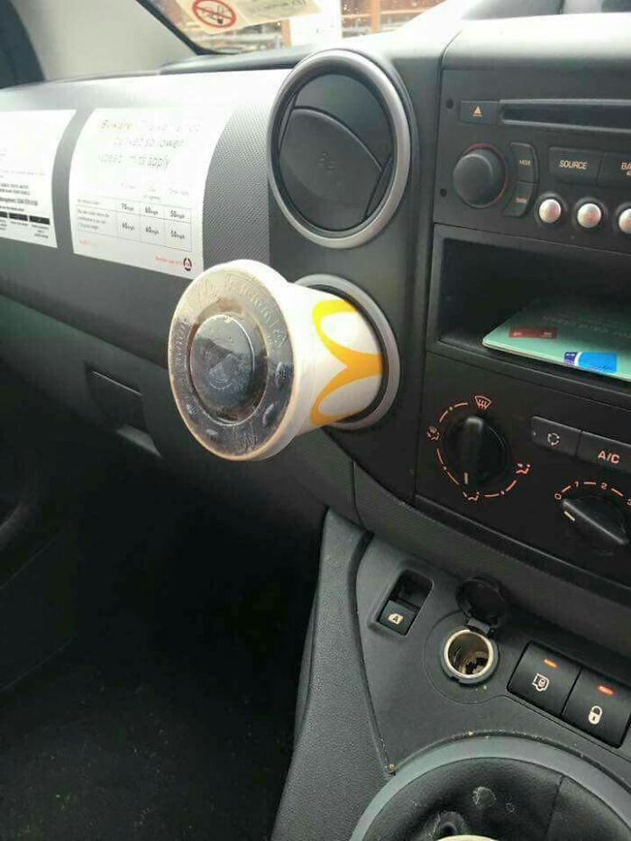 A McDonald's cup used as a car air freshener, an unhinged image of unconventional car accessories.