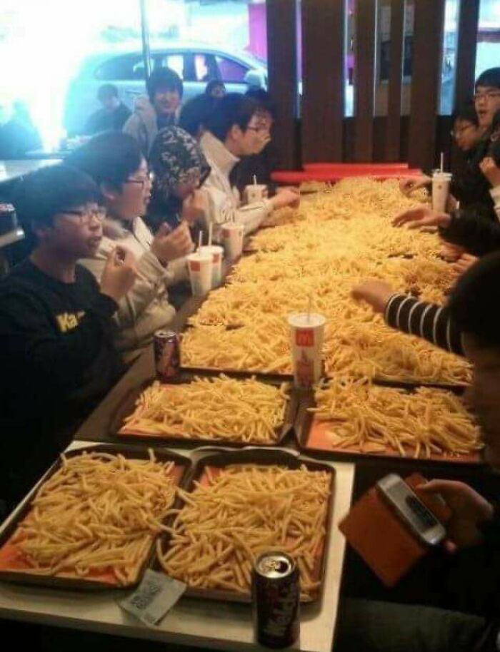 A long table covered entirely with french fries, highlighting an unhinged image of extreme indulgence.