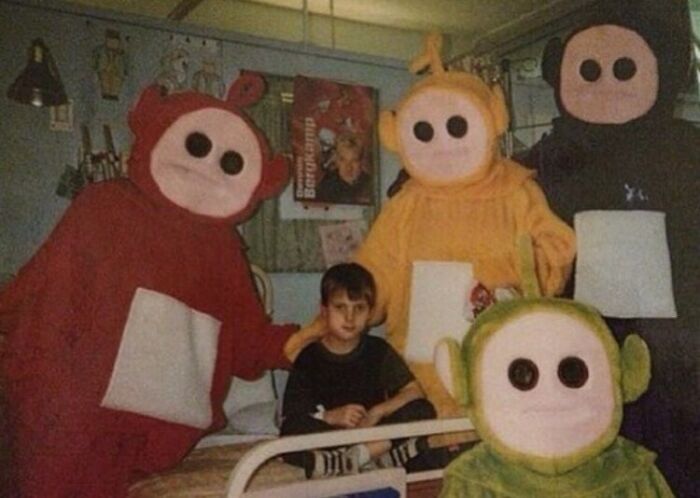 Unhinged images: A young boy sits on a bed surrounded by four creepy, faceless Teletubbies costumes.
