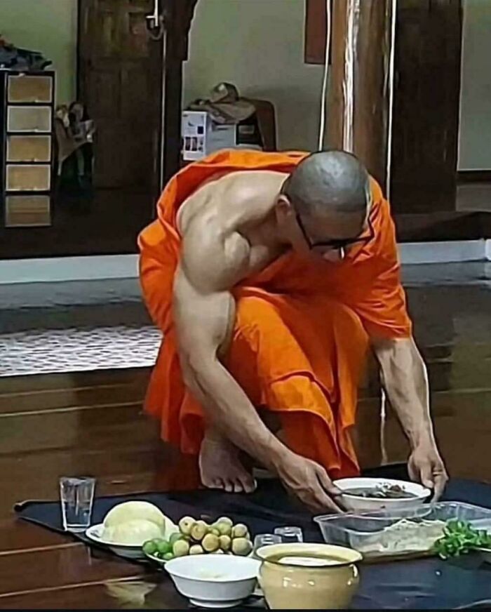A muscular monk in orange robes bending over food, an unhinged image.