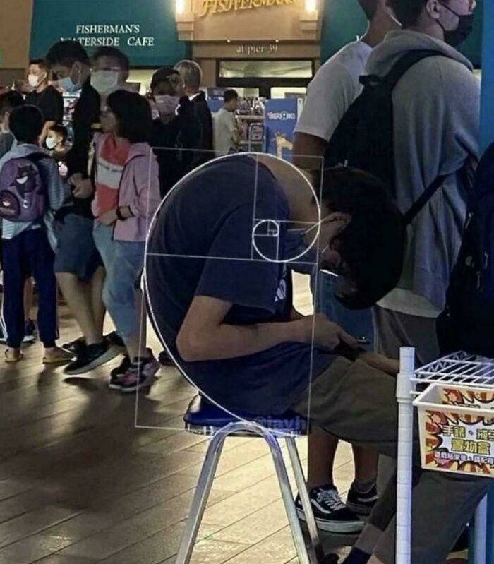 A person hunched over a phone with a Fibonacci spiral overlay, an unhinged image.